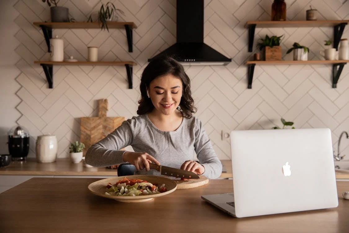 Woman is making herself a salad in front of computer